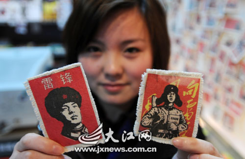 A girl shows two cloth patches bearing the image of Lei Feng that were recently on sale in Nanchang, Jiangxi province on March 4, 2009. The Lei Feng items, including shirts and wallets, are popular among local customers who plan to mark March 5 'Learning from Lei Feng Day.' Lei Feng, an army squad leader who died in an accident in 1962 at an young age of 22, became a household name in 1963 when Chairman Mao called on people to learn from him, an example of selflessness. [Photo: jxnews.com.cn]