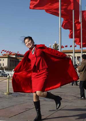 An attendant poses for photos in front of the Great Hall of the People in Beijing, capital of China, March 5, 2009. The Second Session of the 11th National People's Congress (NPC) opened on Thursday. 