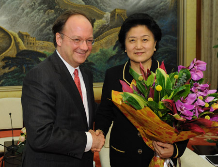 John DeGioia (L), president of Georgetown University of the United States, presents flowers to Chinese State Councilor Liu Yandong to celebrate the International Women's Day during their meeting at the Great Hall of the People in Beijing, capital of China, March 8, 2009. 