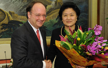 John DeGioia (L), president of Georgetown University of the United States, presents flowers to Chinese State Councilor Liu Yandong to celebrate the International Women's Day during their meeting at the Great Hall of the People in Beijing, capital of China, March 8, 2009.
