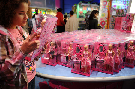 A girl picks up a Barbie doll in the ToysRus at Times Square in New York, the United States, March 7, 2009. Barbie celebrates her 50th birthday on March 9, 2009. (Xinhua/Gu Xinrong)