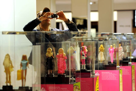 A visitor takes photos of Barbie dolls displayed during an exhibition at a shopping center in New York, the United States, on March 9, 2009. The exhibition held here displayed 120 Barbie dolls of 6 series to celebrate Barbie's 50th birthday. (Xinhua/Shen Hong)