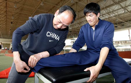 Sun Haiping (L), the coach of Chinese 110m hurdle star Liu Xiang works on Liu's foot prior to a training session in Shanghai, east China, March 10, 2009. [Xinhua]