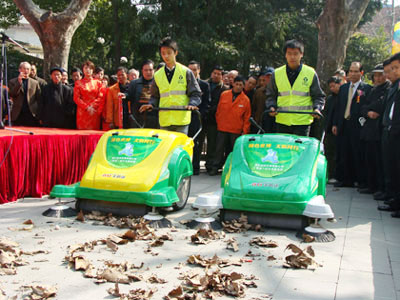 Two sanitation workers demonstrate the effectiveness of the new road-sweepers in Xiangyang Park on Huaihai Road M in Shanghai on Monday, March 9,2009. 