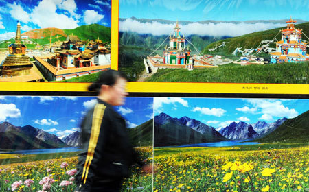 A woman passes the photos of landscapes of southwest China's Tibet Autonomous Region taken by Tibetan photographers in Xining, capital of west China's Qinghai Province, Mar. 10, 2009. A photo studio in Xining held a photography exhibition which displayed works of Tibetan photographers recent days. The works shown on the exhibition includes photos about religion, landscape, festivals and Tibetan traditions. [Xinhua photo]