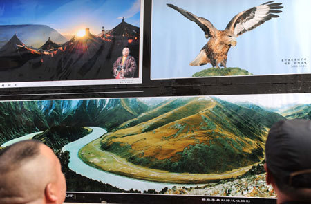 A man watches the photos of landscapes of southwest China's Tibet Autonomous Region taken by Tibetan photographers in Xining, capital of west China's Qinghai Province, Mar. 10, 2009. [Xinhua photo]