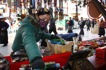 A woman arranges her goods in the famous market street, Pogor near the Jokhang Temple in central Lhasa, capital of southwest China's Tibet Autonomous Region, March 10, 2009. [Xinhua photo]