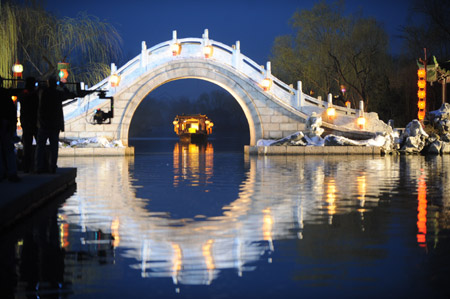The cast and crew of new version TV series screening China's classic romance 'A Dream of Red Mansions' go along with their trial shooting of breakdown scripts, at the illuminated arch bridge in the landscape water zone of the Slim West Lake, in Yangzhou City, east China's Jiangsu Province, March 9, 2009. 