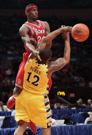 St. John's University's Justin Burrell attempts to pass against the defense of Marquette University's defender Dwight Burke (12) in the second half of their game at the 2009 NCAA Big East men's college basketball tournament in New York March 11, 2009.