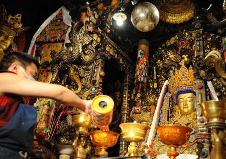 A Lama adds ghee to the lamp in front of the figures of Buddha in the Jokhang Temple in Lhasa, capital of southwest China's Tibet Autonomous Region, Mar. 11, 2009. A celebration for the ghee flowers and lanterns festival was held in the Jokhang Temple, attracting the visitors from all over the country. (Xinhua/Chogo)