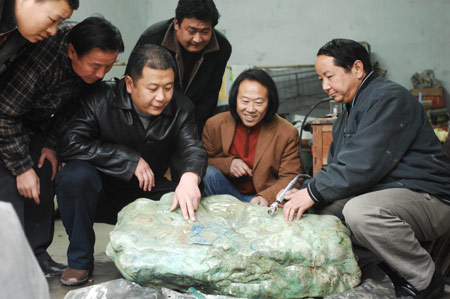 Collector Zhang Wenli (3rd, L) and geological specialist Chen Qiming (1st, R) consult each other's connoisseurship to appraise a super-sized valuable gem of turquoise, which measures some 100 cm in length, 60 cm in height, and 210 kg in weight, in Xiangfan City, central China's Hubei Province, March 10, 2009.(Xinhua/An Fubin)