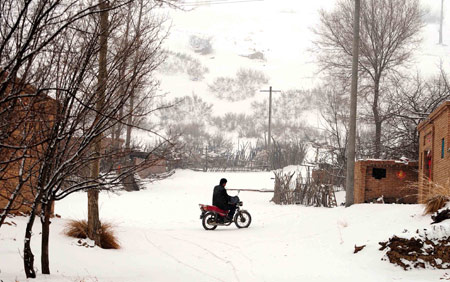 A peasant rides a motorcycle in a town in Ordos, north China's Inner Mongolia Autonomous Region, Mar. 11, 2009. Heavy snow hit central and west parts of the region on Wednesday, drawing the temperature down.(Xinhua/Ren Junchuan)