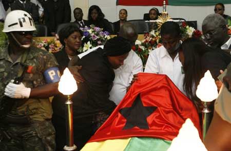 Isabel Vieira, the widow of Guinea-Bissau President Joao Bernardo "Nino" Vieira, looks at the body of her husband during the official funeral at the parliament in Bissau March 10, 2009.