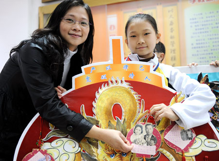 A Taiwanese girl, accompanied by her mother, shows the photo of her family members on a genealogy at No. 1 Primary Schoool attached to Fuzhou Education College, where some Taiwanese children study, in Fuzhou, capital of southeast China's Fujian Province, Mar. 11, 2009. Pupils from two sides of the Taiwan Straits display their handmade genealogies to express the compatriots' affection on Wednesday. (Xinhua/Jiang Kehong) 
