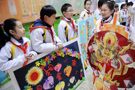 A Taiwanese girl (R, front), carrying her handmade genealogy, talks with schoolmates at No. 1 Primary Schoool attached to Fuzhou Education College, where some Taiwanese children study, in Fuzhou, capital of southeast China's Fujian Province, Mar. 11, 2009. Pupils from two sides of the Taiwan Straits display their handmade genealogies to express the compatriots' affection on Wednesday. (Xinhua/Jiang Kehong) 
