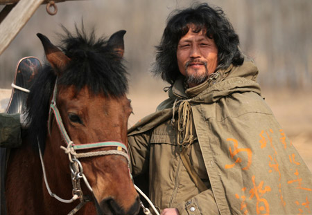 Chinese-Russian Li Jing stands beside his horse at Changping District of Beijing, capital of China, Mar. 10, 2009. Li arrived in Beijing Monday after his 9,000-kilometer journey of riding across the Eurasia alone starting from the Republic of Bashkortostan, Russia, on August 21, 2007. (Xinhua/Zhou Guoqiang)