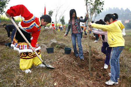 Students of Suining plant a sapling presenting friendship with a student of Tibet ethnic group in Suining City, southwest China's Sichuan Province, Mar. 11, 2009. More than 200 Tibetan students of Wolong primary school in Wenchuan County have been transfered to Suining for education after the earthquake happened on May. 12, 2008. [Xinhua photo]