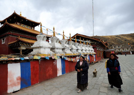 People walk by the building of Lhakang Temple, 110 kilometers to Kangding city in southwest China's Sichuan Province, March 4, 2009. [Xinhua Photo]
