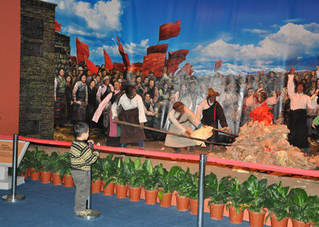 A boy watches a simulated scenario featuring serfs burning feudal documents produced in old Tibet after the Democratic Reform at an exhibition marking the 50th anniversary of the Democratic Reform in Tibet Autonomous Region in Beijing, Feb. 25, 2009. (Xinhuanet Photo)