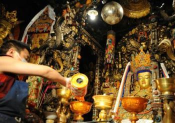 A Lama adds ghee to the lamp in front of the figures of Buddha in the Jokhang Temple in Lhasa, capital of southwest China&apos;s Tibet Autonomous Region, Mar. 11, 2009. A celebration for the ghee flowers and lanterns festival was held in the Jokhang Temple, attracting the visitors from all over the country. [Chogo/Xinhua] 