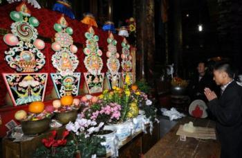 Believers worship the colorful ghee figures of Buddha in the Jokhang Temple in Lhasa, capital of southwest China's Tibet Autonomous Region, Mar. 11, 2009. A celebration for the ghee flowers and lanterns festival was held in the Jokhang Temple, attracting the visitors from all over the nation. [Chogo/Xinhua] 