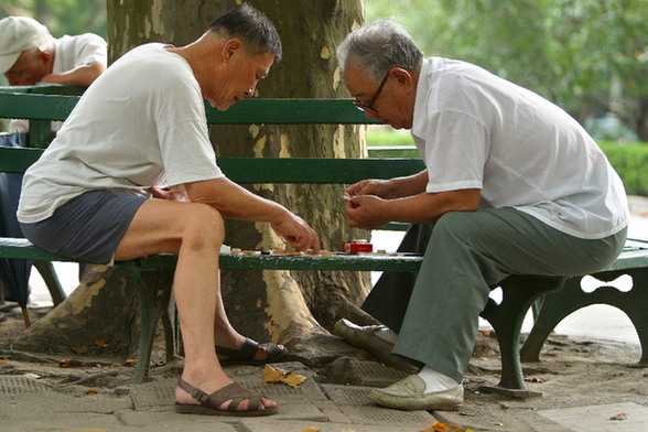 Senior citizens playing chess in a park. 