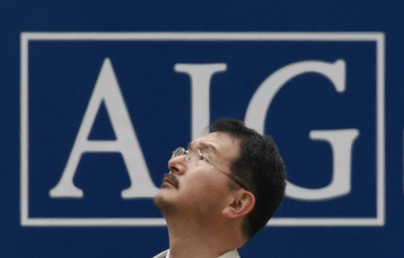 A man stands in front of an AIG logo in Tokyo March 3, 2009. Japan's Nikkei stock average touched a four-month low on Tuesday but later pared losses to 1 percent, with banks such as Mizuho Financial Group down on fear about the U.S. financial system after AIG posted huge losses. [Xinhua]