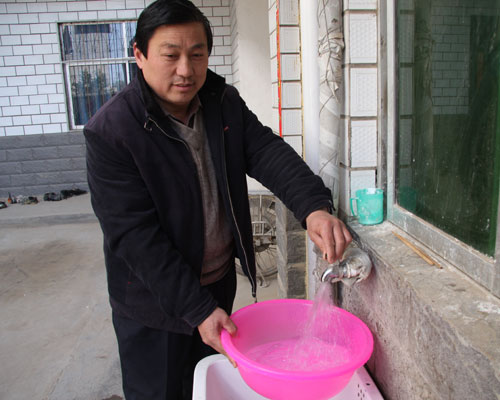 42-year-old Wang Jianniu turns the tap off in his yard on Saturday, March 14, 2009. All the residents in Qiancheng Village, Zhongmu County, in central Henan Province have used clean tap water as a result of the county's large-scale 'safe drinking water' program. [Photo: CRIENGLISH.com]