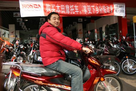 A local youth rides his just-purchased motorcycle on promotion sales with governmental subsidies to countryside, in Meishan, southwest China's Sichuan Province, March 15, 2009. China implements new sets of tax cuts and subsidies to boost demand for cars, with the intention on encouraging purchases of cars and other vehicles, especially in the vast countryside. They are meant to help autos and auto parts makers upgrade to more modern, energy-efficient technology. (Xinhua)