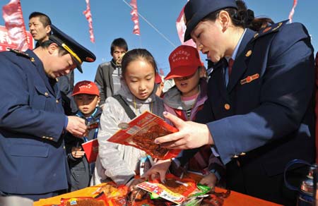 Officers from local commerce administration talk with students about food safety during an event to mark the World Consumer Rights Day in Yinchuan, Ningxia Hui Autonomous Region, March 15, 2009.