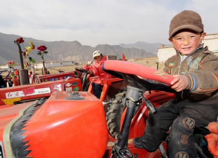 A boy sits in a tractor during a ceremony to mark the start of the spring farming season at Dagze County, southwest China's Tibet Autonomous Region, March 15, 2009. [Chogo/Xinhua] 