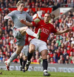 Manchester United's Nemanja Vidic (R) challenges Liverpool's Fernando Torres during their English Premier League soccer match in Manchester, northern England, March 14, 2009. [Xinhua/Reuters]