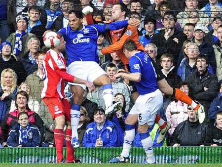 Stoke City's Tomas Sorensen (R) punches the ball away from Everton's Joleon Lescott (C) during their English Premier League soccer match in Liverpool March 14, 2009. [Xinhua/Reuters]