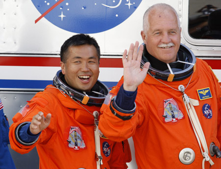 Space shuttle Discovery astronaut Koichi Wakata (L) of Japan and John Phillips wave as they depart with other crew members for launch pad 39A at the Kennedy Space Center in Cape Canaveral, Florida March 15, 2009.[Xinhua/Reuters]