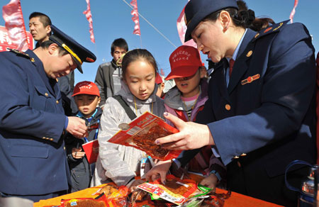 Officers from local commerce administration talk with students about food safety during an event to mark the World Consumer Rights Day in Yinchuan, Ningxia Hui Autonomous Region, March 15, 2009. Lots of such events were held across China on Sunday.[Wang Peng/Xinhua]