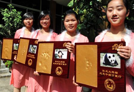 Volunteers display the footprints of pandas in Fuzhou, southeast China's Fujian Province, March 15, 2009. An activity titled '10,000 Miles March of Thanks' was held here by Wolong China Panda Protection Research Center. The Wolong Panda Breeding Base was damaged in the earthquake in 2008, and pandas were removed to eight cities, namely Beijing, Chengdu, Nanjing, Kunming, Fuzhou, Zunyi, Wuhan and Guangzhou. [Zhang Guojun/Xinhua] 