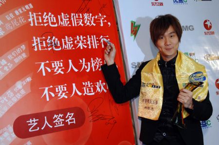 Singaporean Wayne Lin Junjie, a pop singer high on the top 5 of the grand Chinese pops by the 16th Oriental Wind and Cloud Music Rankings, one of the most influential pop music ranking for lyrics in Chinese on Chinese mainland, puts signature on the board with epigram reminder for pop singers' virtues, during the awarding ceremony held in east China's Shanghai Municipality, March 15, 2009. The awards of best male and female pop singers are presented to Sun Nan and Zhang Liangying of Chinese mainland.