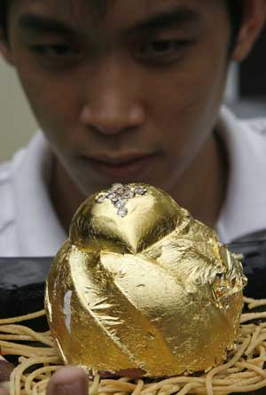 Businessman Angelito Araneta Jr., 21, shows a chocolate cake topped with 15 African diamonds and covered with 24-karat gold leaves, which he displayed at his residence in Manila March 16, 2009. Araneta, who commissioned his catering service to create the cake, says he plans to sell the cake at 124,000 pesos (2,558 U.S. dollars) to men for use as a marriage proposal gift.[Xinhua/Reuters]