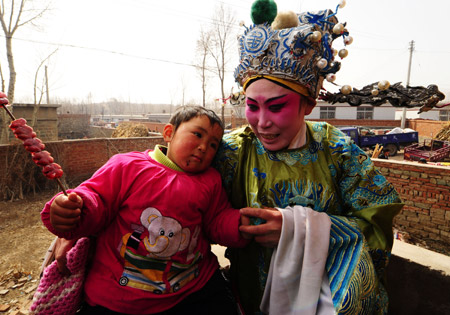 Chen Xiangmei (R), a local actress, plays with her daughter Wang Rui during an interval of a performance at Halagui Village in Chaoyang County, northeast China's Liaoning Village, March 15, 2009. [Ren Yong/Xinhua]