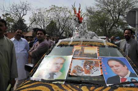  People gather beside a car with posters of Former Prime Minister Nawaz Sharif (R) and his brother in Islamabad, capital of Pakistan, March 16, 2009. [Rao Bo/Xinhua]