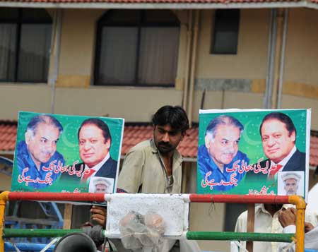 A Supporter of restored Chief Justice Iftikhar Muhammad Chaudhry walks past the posters of Former Prime Minister Nawaz Sharif (R) and his brother outside Chaudhry's residence in Islambad, capital of Pakistan, March 16, 2009. [Rao Bo/Xinhua]