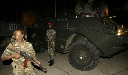 Soldiers stand guard by a military vehicle, after two tanks backed by troops forced their way into a presidential palace, in Antananarivo March 16, 2009. [China Daily/Agencies]