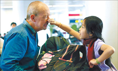 Nine-year-old Nikki playfully tweaks the nose of her adoptive father, American Ray Crete, at Beijing Capital International Airport yesterday. They were part of 34 foreign families invited by the Ministry of Civil Affairs to visit Yangzhou, Jiangsu province, where the children were adopted. [Wang Jing/China Daily] 