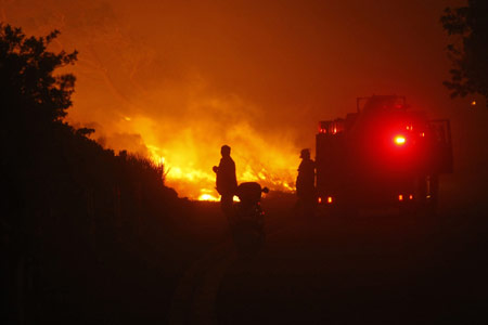 Firefighters battle flames as a massive bush fire threatens buildings as it sweeps across Cape Town's Table Mountain, March 18, 2009,causing hundreds of people to be evacuated. Strong south easterly winds, coupled with hot dry weather, have fanned hundreds of bush fires across the province in recent weeks. [Xinhua/Reuters]