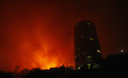 A massive bush fire threatens buildings as it sweeps across Cape Town's Table Mountain, March 18, 2009,causing hundreds of people to be evacuated. Strong south easterly winds, coupled with hot dry weather, have fanned hundreds of bush fires across the province in recent weeks. [Xinhua/Reuters]