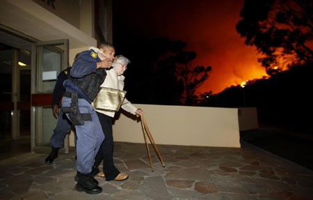 Police evacuate elderly residents as a massive bush fire sweeps across Cape Town's Table Mountain in South Africa, March 18, 2009. [China Daily/Agencies]