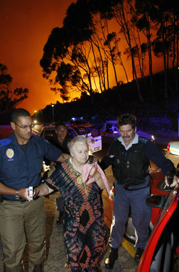 Police evacuate elderly residents as a massive bush fire sweeps across Cape Town's Table Mountain in South Africa, March 18, 2009. [China Daily/Agencies] 