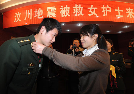 Duan Zhongying (R), a survivor of last year's Sichuan earthquake, gives an amulet to Yu Feng, one of the firemen who rescued her, in Yangzhou, east China's Jiangsu Province, March 17, 2009. 