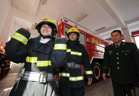 Duan Zhongying (L), a survivor of last year's Sichuan earthquake, tries on a fireman uniform in Yangzhou, east China's Jiangsu Province, March 17, 2009. [Wang Zhuo/Xinhua]