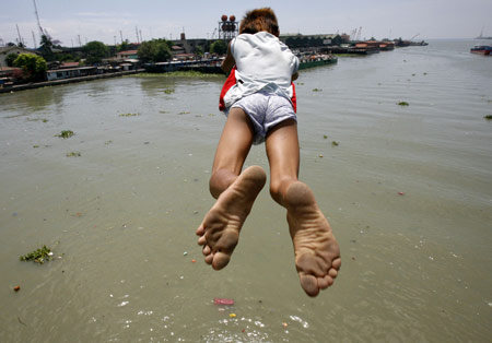 A boy dives into polluted Manila bay to beat the simmering heat March 18, 2009. The summer season officially started on the last week of February and is expected to end around the second week of May. [Xinhua/Reuters]